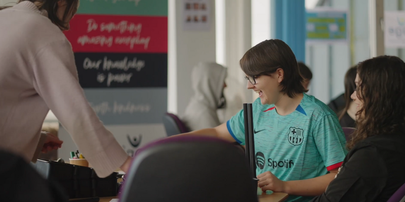 Three young people working at a desk together smiling.