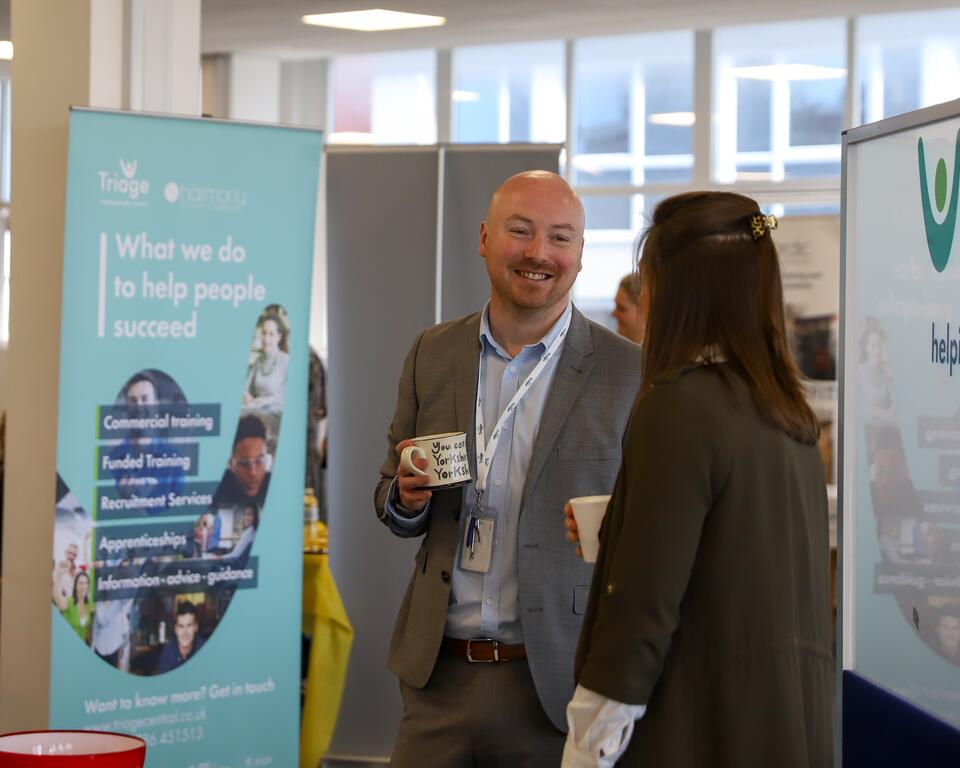 Man smiling at woman beside a Triage artwork banner