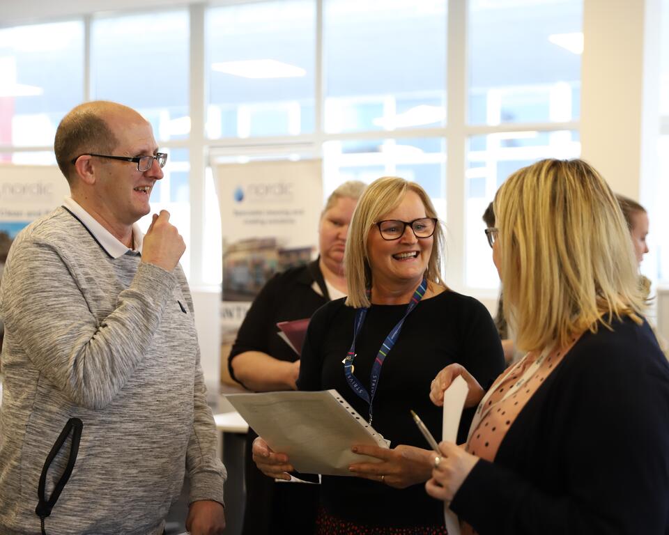 Two women and man talking and laughing.