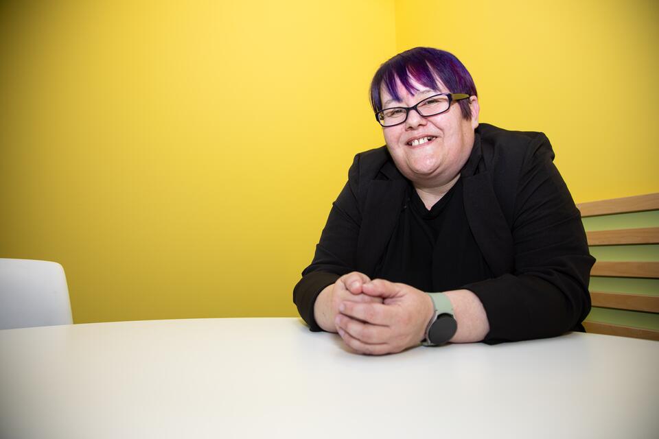 Woman smiling at camera sitting at desk with hands crossed
