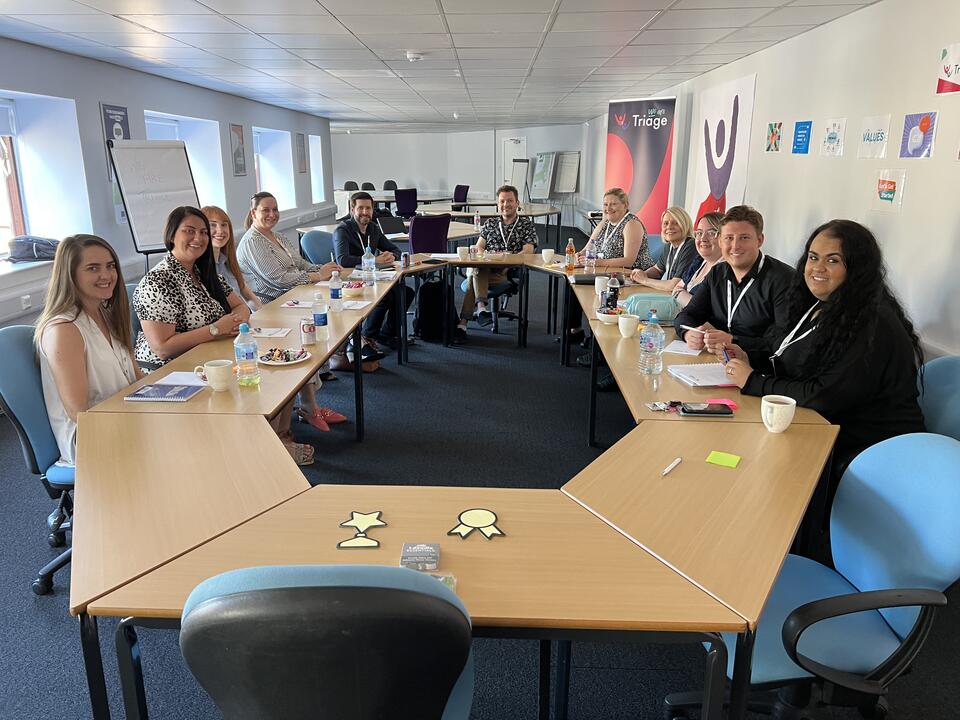 11 Triage colleagues sitting round a table talking