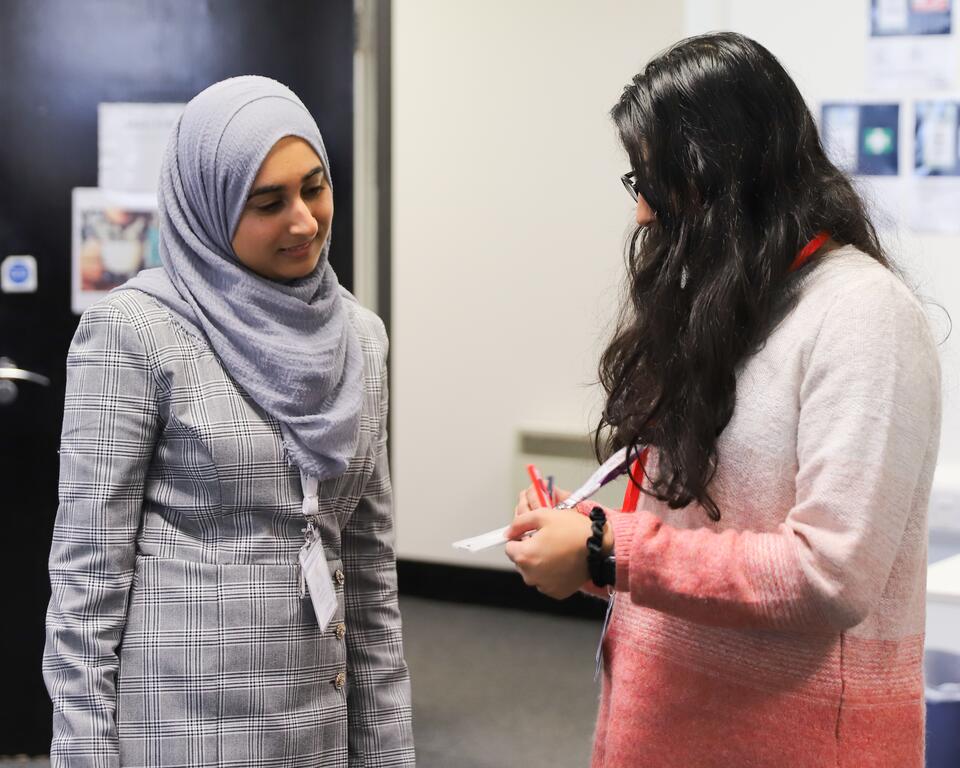 Two women deep in conversation. One woman is showing the other a leaflet. 