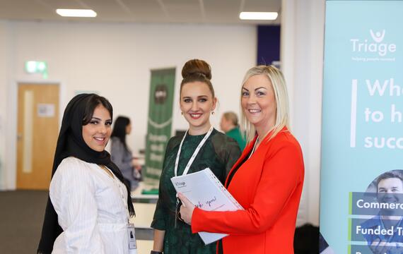 Three women posing for camera in an office.
