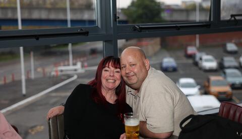 Man and woman sitting with a pint of beer, posing for photo