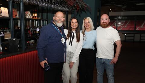 Two men and two women standing in a bar posing for a photo