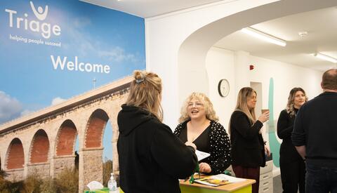 Busy office with people talking and a image saying welcome