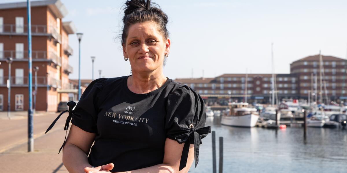 Woman smiling at camera leaning against railings beside a marina