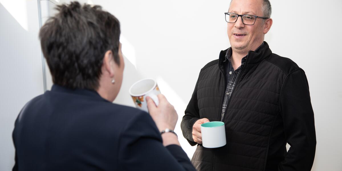 Man drinking tea with a Triage employee with her back to the camera.