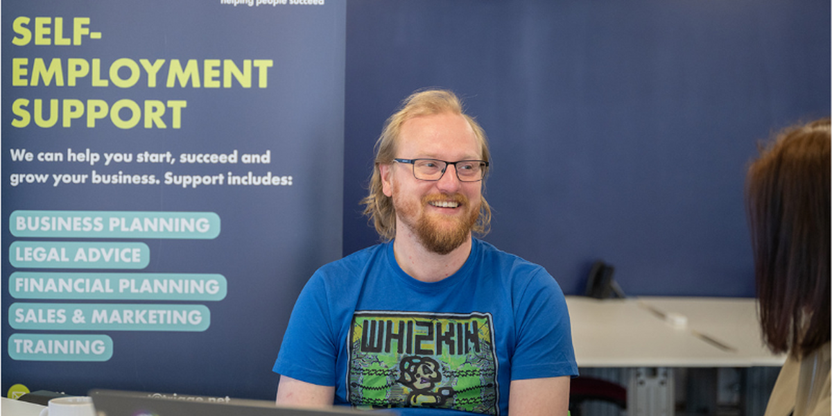 Man in blue branded Whizkin tshirt wearing glasses.