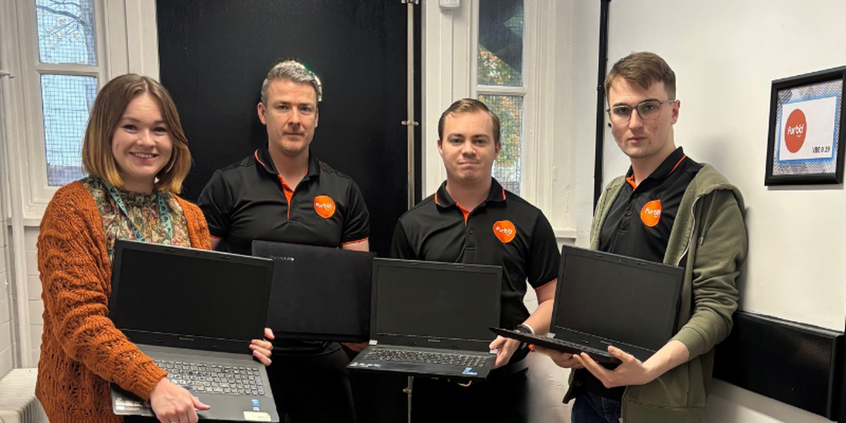 Woman and three men holding laptops and smiling at the camera. Men are all wearing black polos with orange Furbd logo.