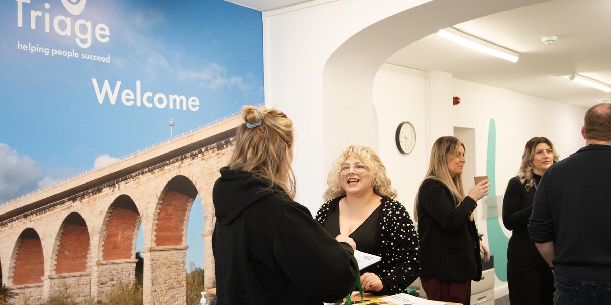 Busy office with people talking and a image saying welcome