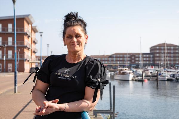 Woman smiling at camera leaning against railings beside a marina