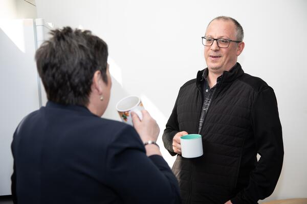 Man drinking tea with a Triage employee with her back to the camera.