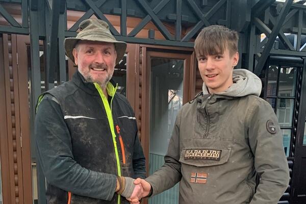 Young man and his manager dressed in mucky gardening clothes shaking hands.