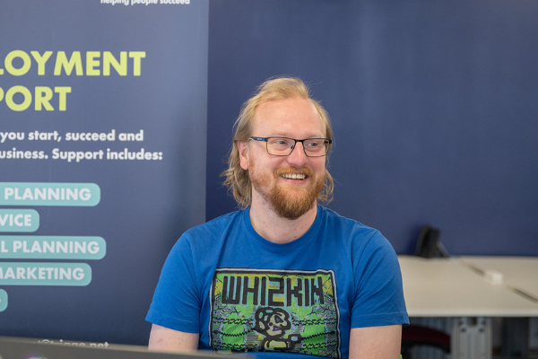 Man in blue branded Whizkin tshirt wearing glasses.