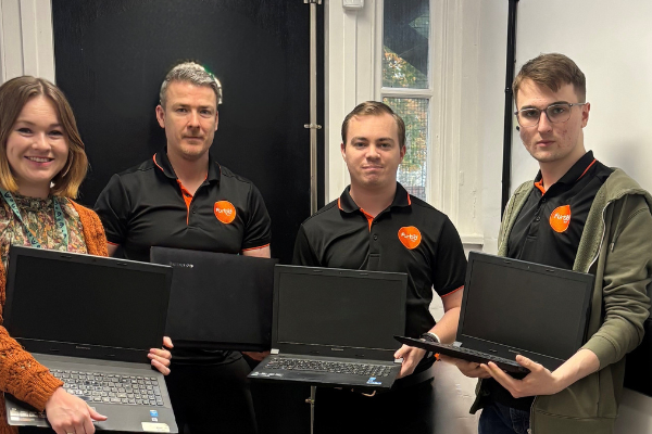 Woman and three men holding laptops and smiling at the camera. Men are all wearing black polos with orange Furbd logo.