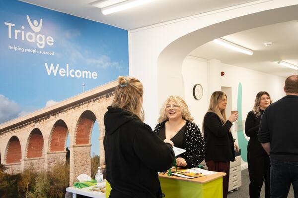 Busy office with people talking and a image saying welcome